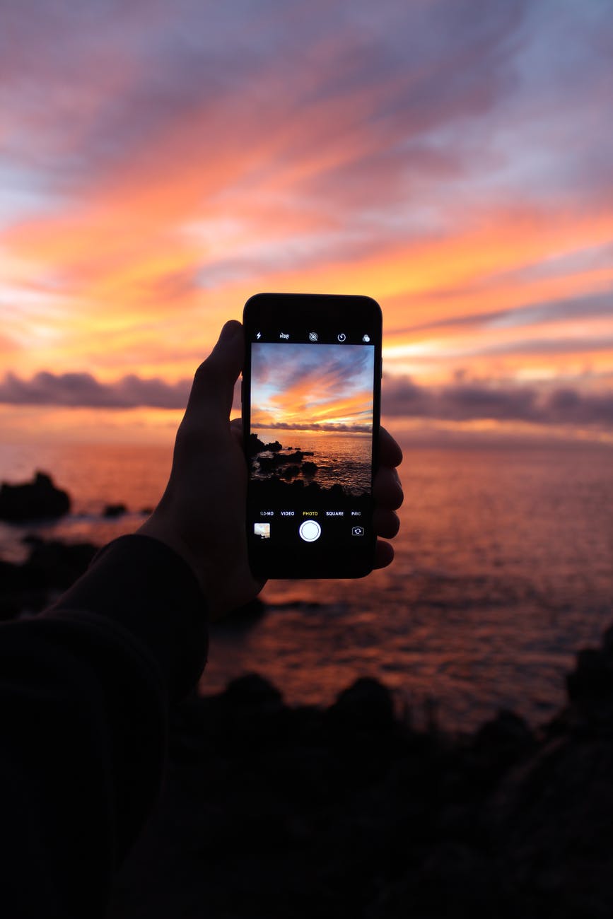 person taking photo of sunset